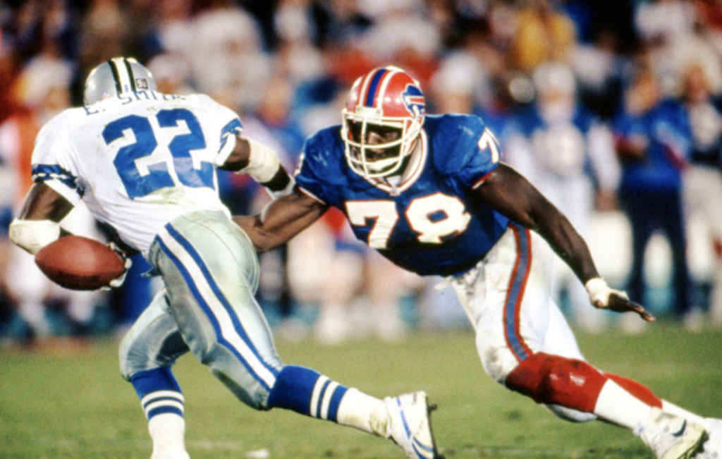 Two men playing football. One man tackling the other one while he runs with the ball